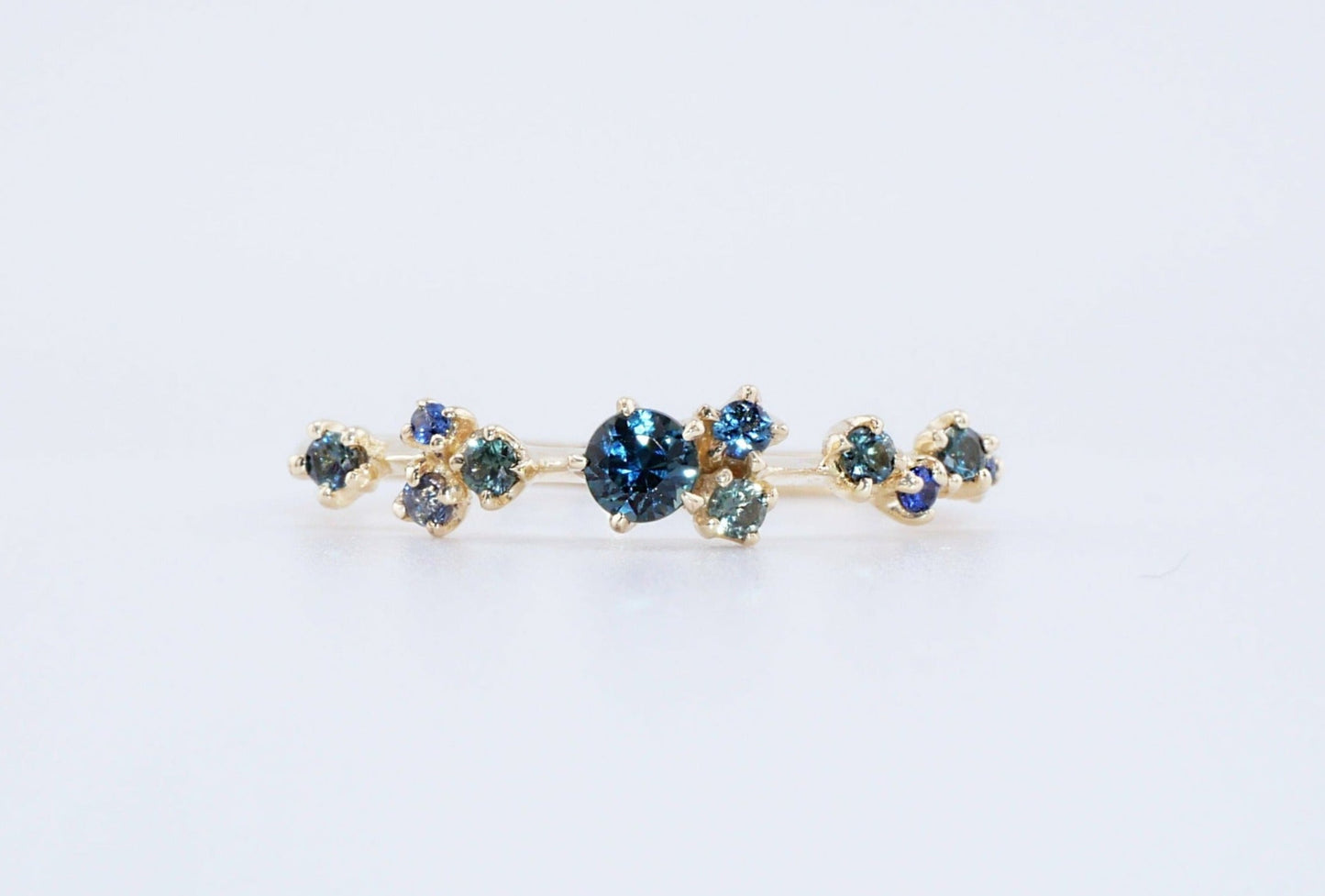 A cluster of blue green sapphires on a thin gold ring band, made by Vazana. 