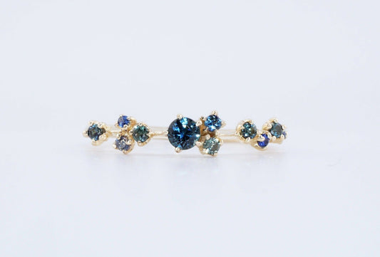 A cluster of blue green sapphires on a thin gold ring band, made by Vazana. 