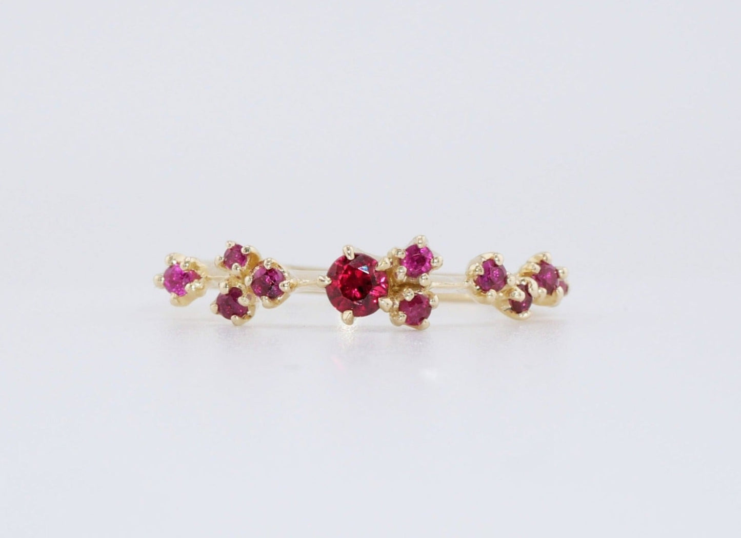 A cluster of rubies dancing on a thin gold ring band, the Lumi Ring from Vazana.